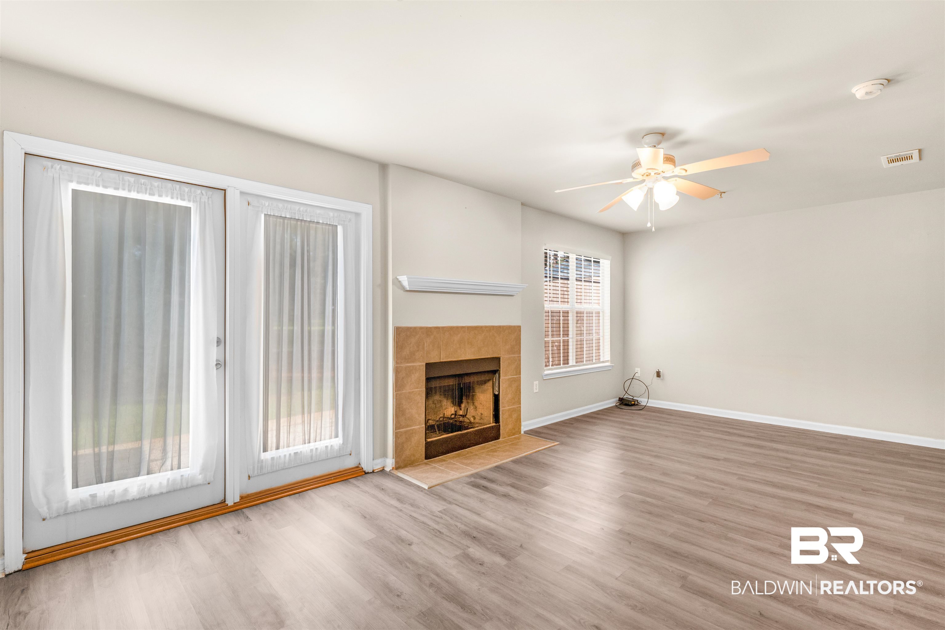 1517 Regency Road, Unit 85 Gulf Shores, AL 36542 - Photo 4 of 32 Unfurnished living room with ceiling fan, a wealth of natural light, light hardwood / wood-style flooring, and a fireplace