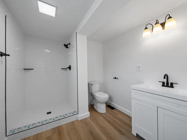 a bathroom with a granite countertop sink a toilet and shower