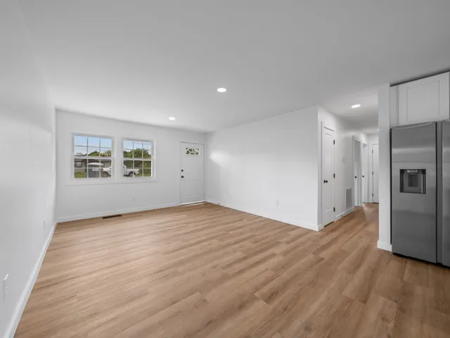 a view of an empty room with a window and a refrigerator