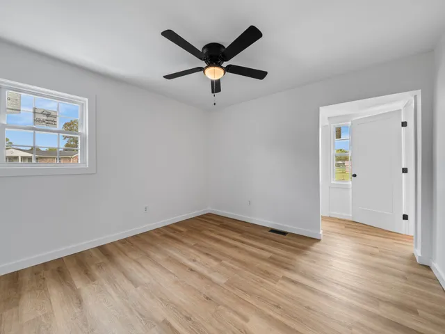 a view of empty room with wooden floor and ceiling fan