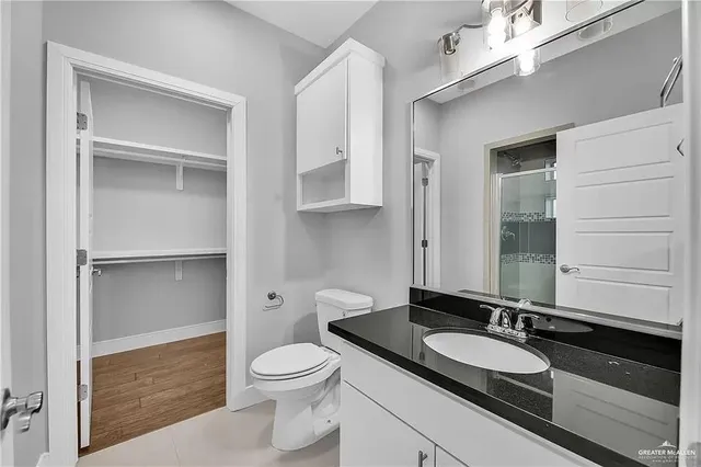 a bathroom with a granite countertop sink a toilet and a mirror