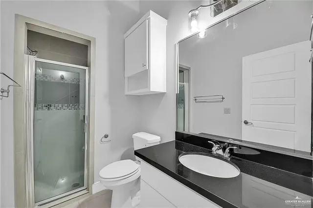 a bathroom with a granite countertop sink toilet a mirror and shower