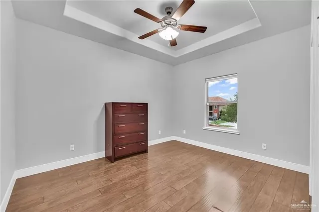 an empty room with windows and ceiling fan