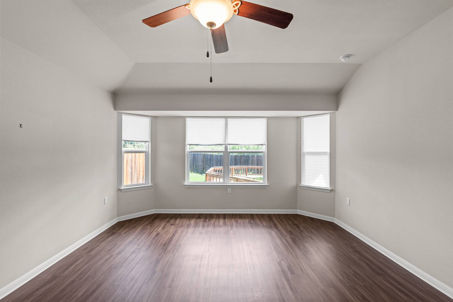 16512 Enamorado Road Manor, TX 78653 - Photo 9 of 31 A spacious room features rich wood flooring, a ceiling fan, and bay windows that offer tranquil views of the backyard.