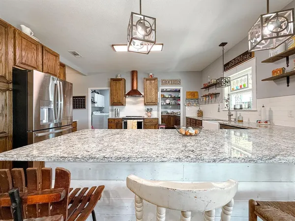 a kitchen with kitchen island granite countertop a sink and refrigerator