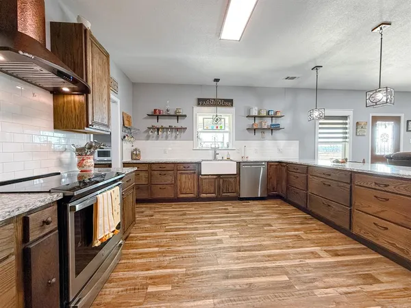 a large kitchen with stainless steel appliances granite countertop a stove a sink dishwasher and a microwave oven with large wooden cabinets