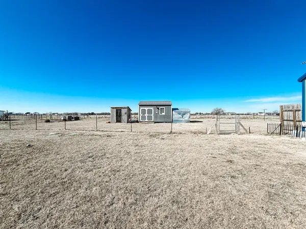a view of a dry yard with wooden fence