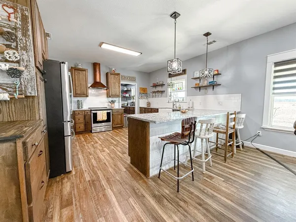 a dining hall with stainless steel appliances granite countertop a stove and a wooden floors