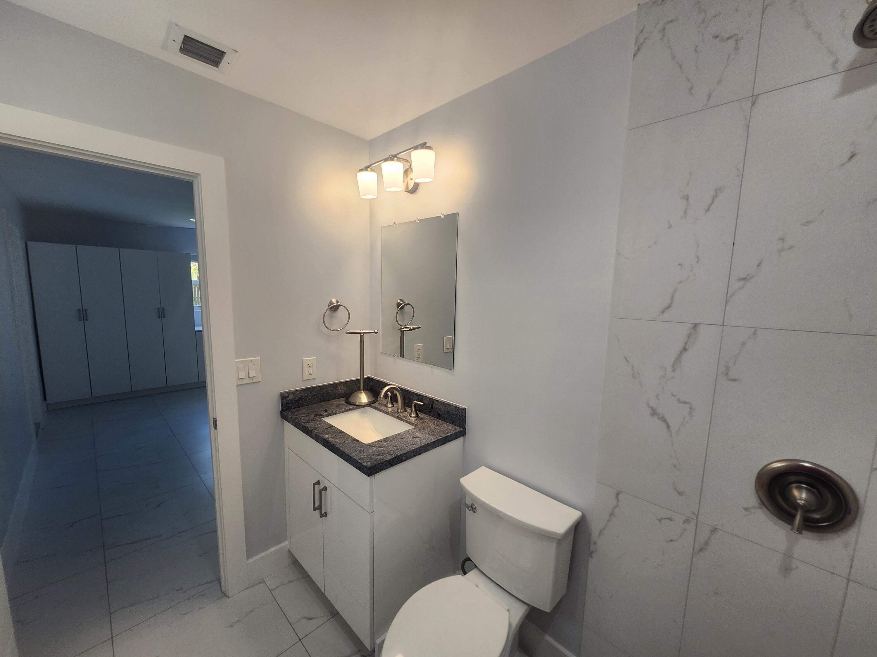 511 Northwest 60th Way, Unit EAST APARTMENT Hollywood, FL 33024 - Photo 13 of 15 a bathroom with a toilet sink and mirror