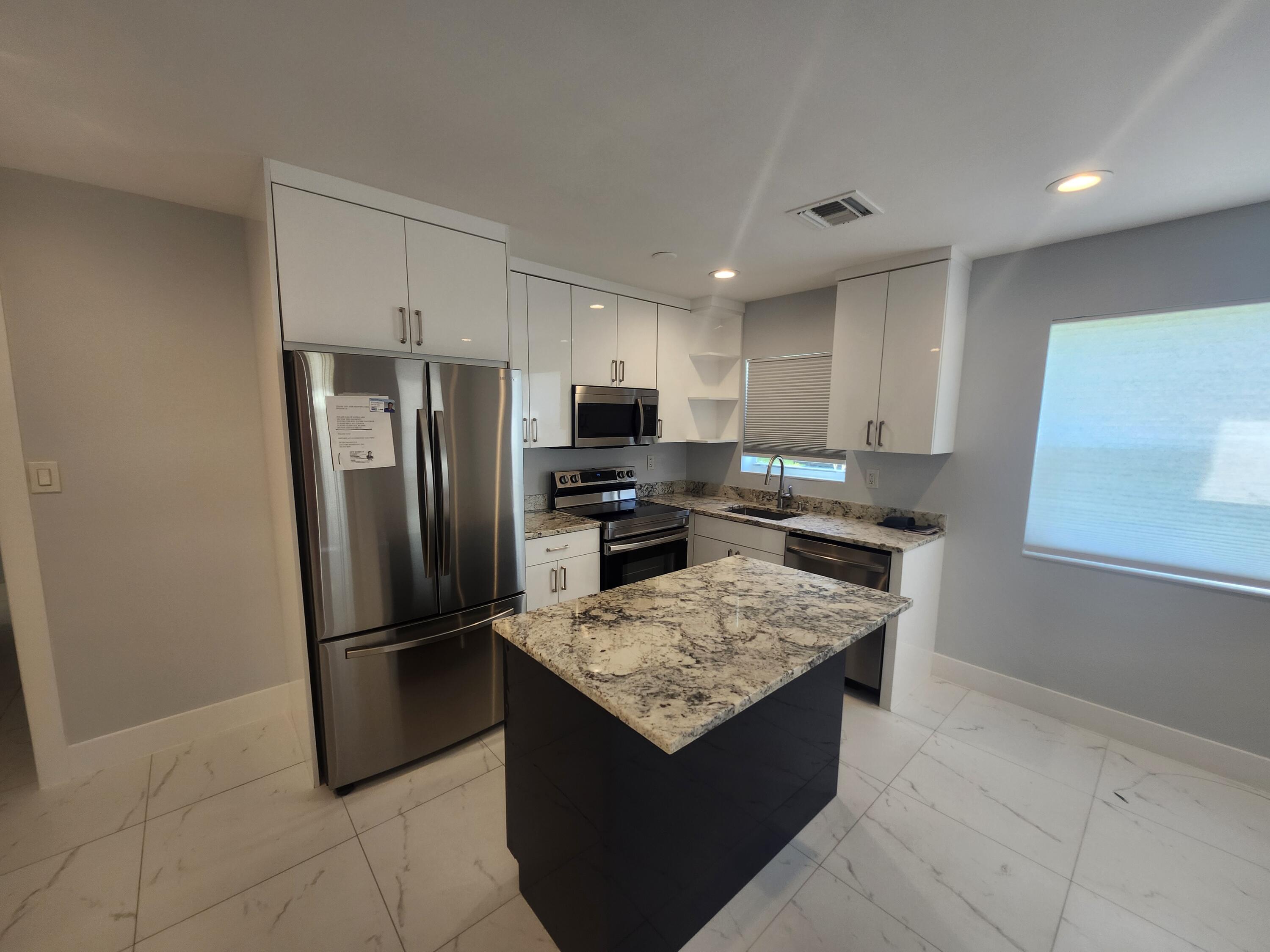 511 Northwest 60th Way, Unit EAST APARTMENT Hollywood, FL 33024 - Photo 8 of 15 a kitchen with a refrigerator a microwave a sink and a stove