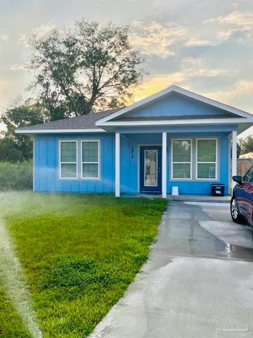 a view of a brick house with a yard plants and large tree