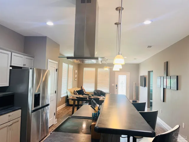 a kitchen with stainless steel appliances a dining table chairs a refrigerator and cabinets