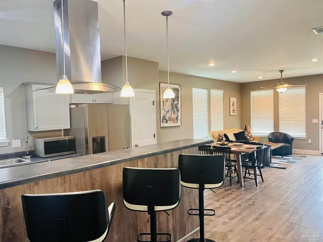 a kitchen with stainless steel appliances granite countertop a stove a sink a microwave a dining table and chairs with wooden floor