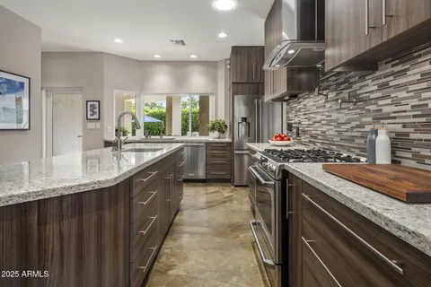 a kitchen with stainless steel appliances kitchen island granite countertop a stove a sink a dining table and chairs