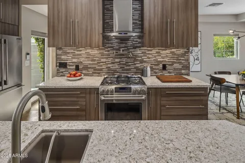 a kitchen with stainless steel appliances granite countertop a sink a stove and a wooden cabinets