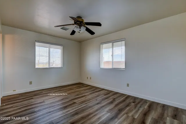 a view of room with hardwood floor ceiling fan and a window