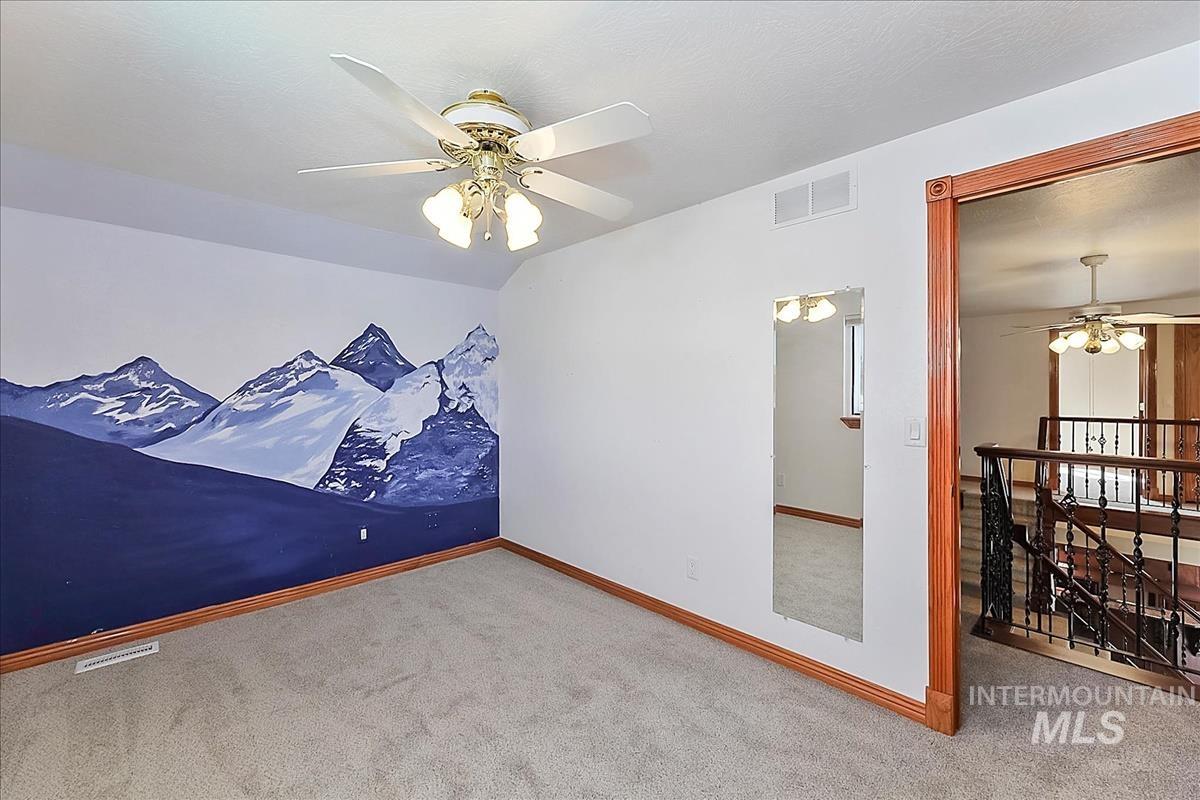 2804 West Sunrise Rim Road Boise, ID 83705 - Photo 26 of 50 Carpeted room featuring a ceiling fan with integrated lighting, a mountain mural accent wall, and wood trim