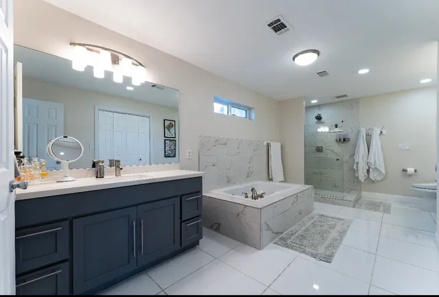a bathroom with a double vanity sink mirror and bathtub