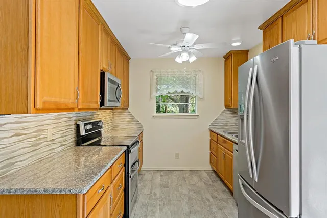 a kitchen with stainless steel appliances granite countertop a refrigerator a stove and a sink with wooden floor