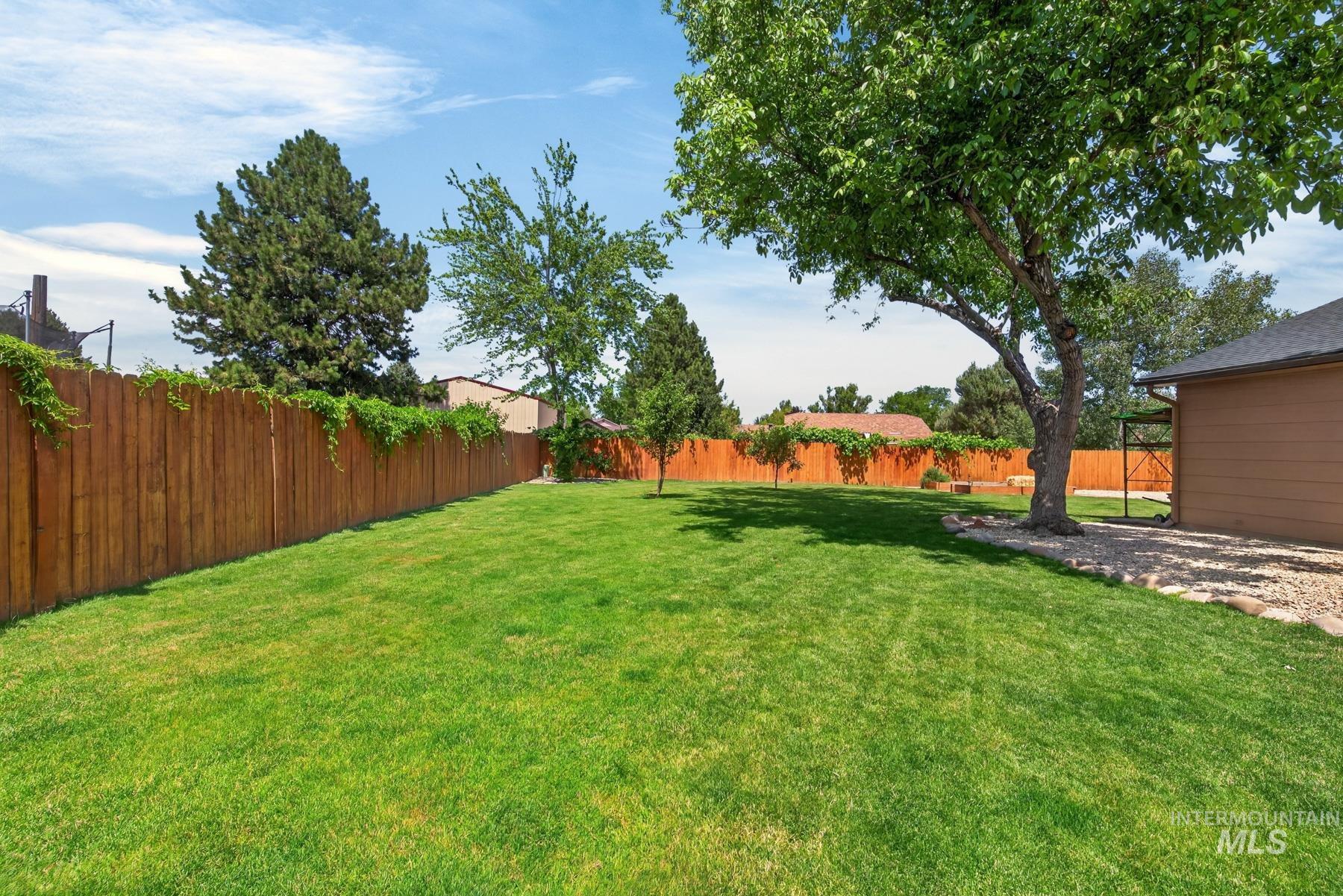 9622 Delaware Street Boise, ID 83709 - Photo 41 of 48 Spacious backyard featuring a lush lawn, mature trees, privacy fencing, and exterior wall siding