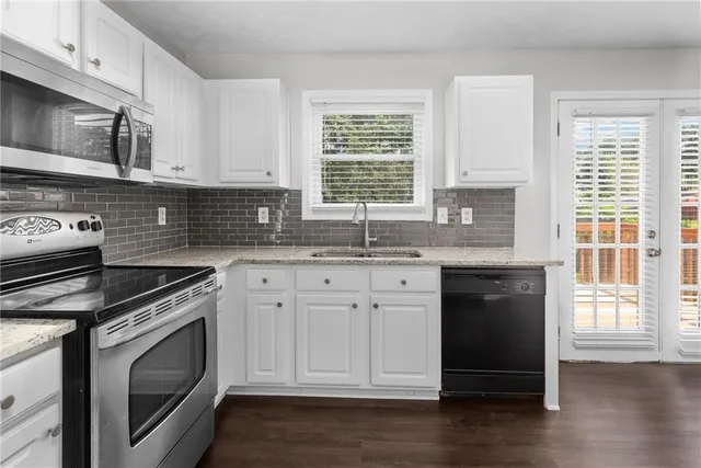 a kitchen with granite countertop white cabinets and stainless steel appliances