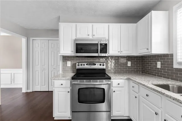 a kitchen with granite countertop a refrigerator and cabinets
