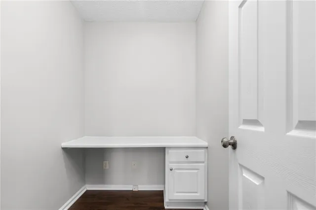 a view of an empty room with wooden floor and a ceiling fan