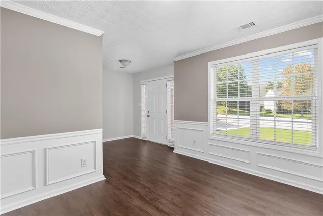 a view of an empty room with wooden floor fireplace and a window