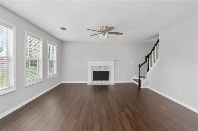 a view of an empty room with wooden floor and a ceiling fan