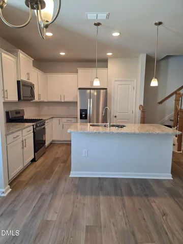 a kitchen with kitchen island granite countertop a stove a sink and a wooden floors