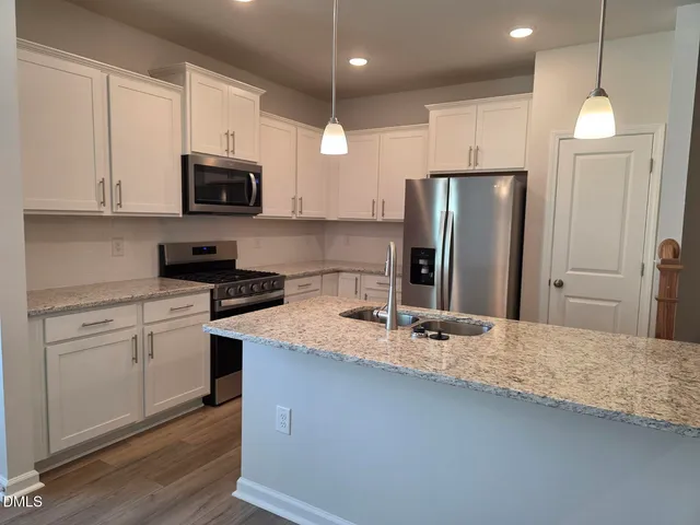 a kitchen with stainless steel appliances granite countertop a refrigerator a stove a sink and a microwave