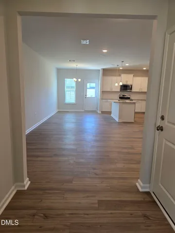 a view of kitchen and empty room with wooden floor