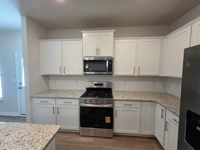 a kitchen with granite countertop white cabinets and black appliances