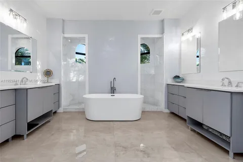 a bathroom with a double vanity sink mirror and bathtub