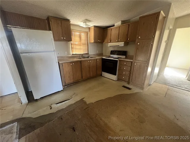 a kitchen with granite countertop a refrigerator a sink a stove a microwave a counter top and cabinets