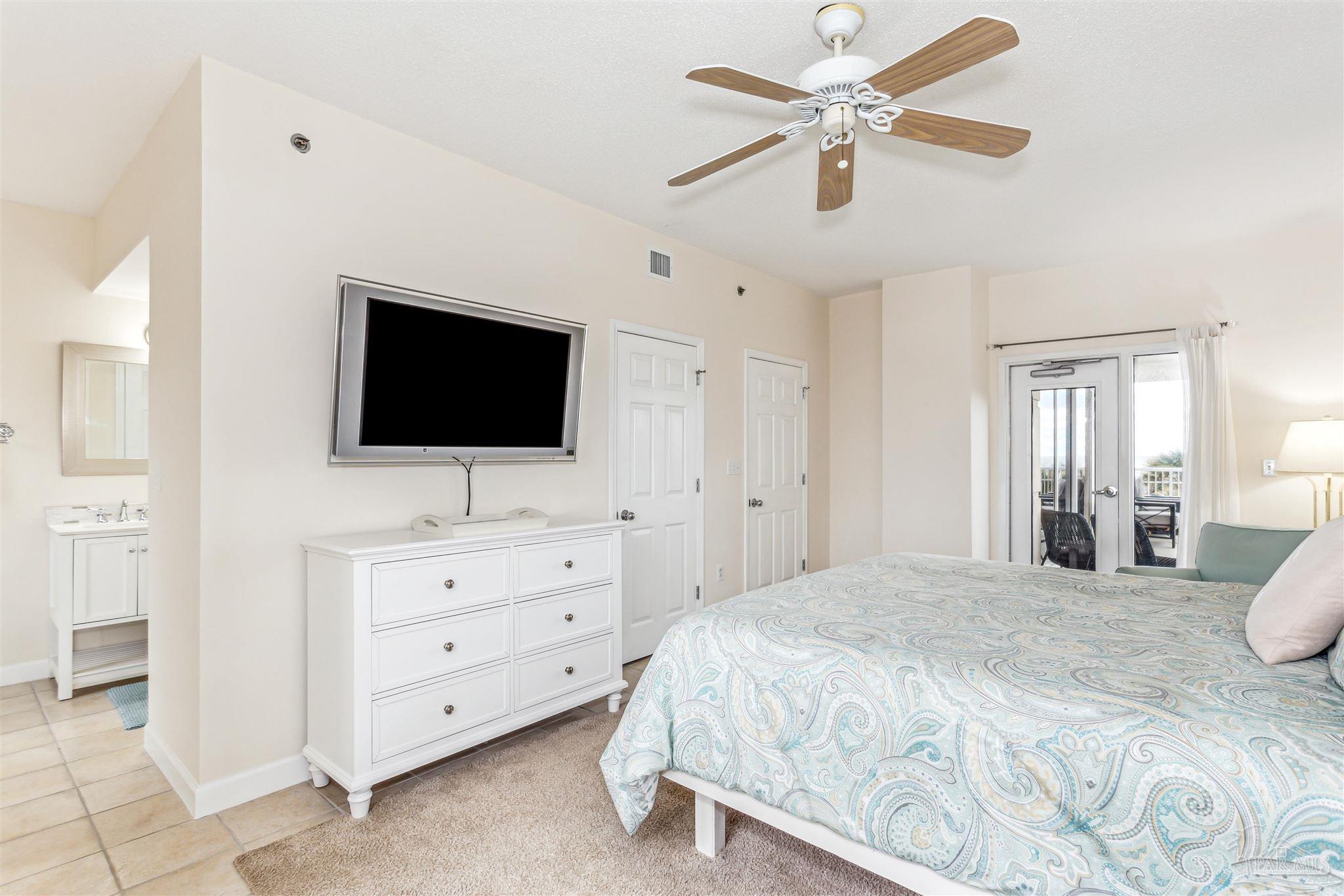 800 Fort Pickens Road, Unit 204 Pensacola Beach, FL 32561 - Photo 30 of 45 a bedroom with a bed a mirror on dresser and a flat screen tv