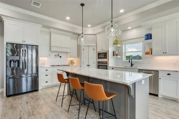 a kitchen with stainless steel appliances a center island wooden floor and a refrigerator