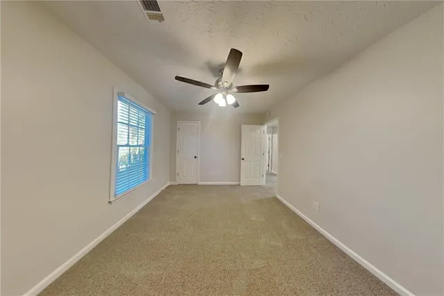 an empty room with windows and fan