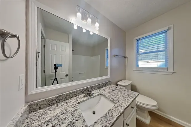 a bathroom with a granite countertop sink a toilet and a mirror