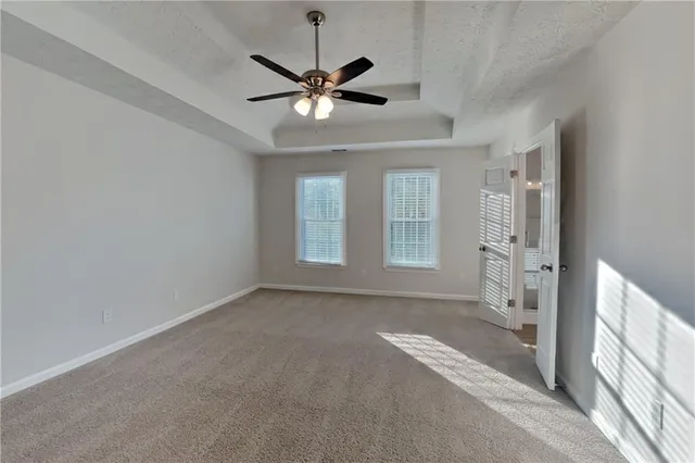 an empty room with chandelier fan and windows