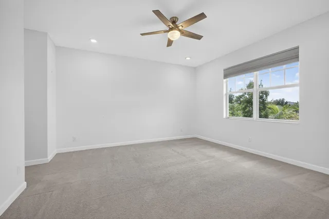 an empty room with a window and a ceiling fan