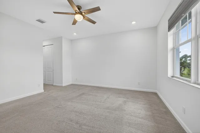 an empty room with windows and fan