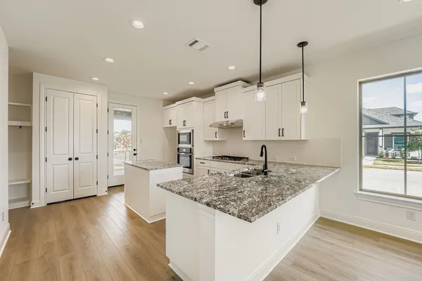 a large kitchen with stainless steel appliances granite countertop a sink a oven a counter space and wooden floor