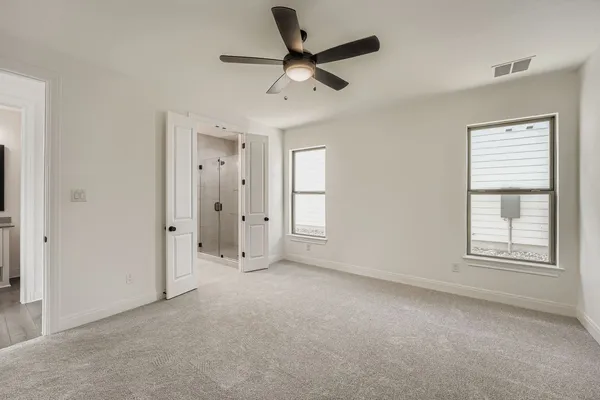 an empty room with chandelier fan and windows