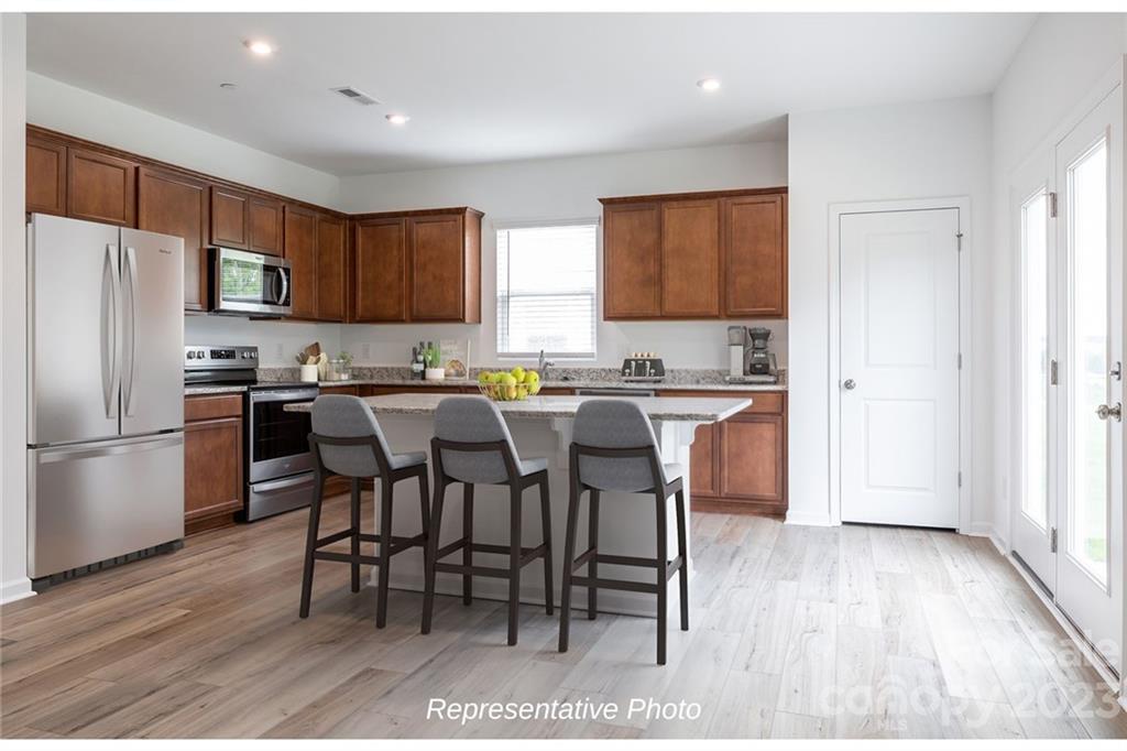 1244 Maple Shade Road Southwest, Unit 73 Concord, NC 28027 - Photo 4 of 12 a kitchen with refrigerator cabinets dining table and chairs