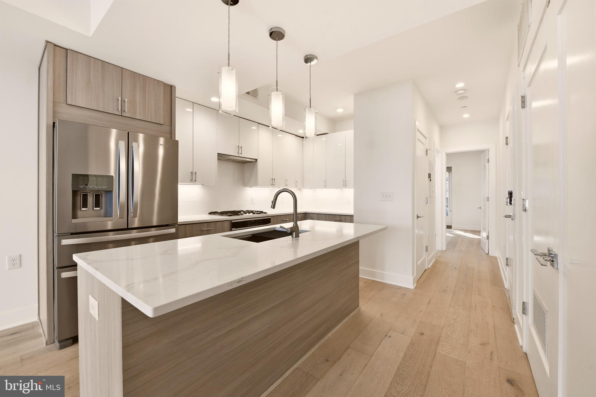 1023 16th Street Northeast, Unit B Washington, DC 20002 - Photo 5 of 25 a large kitchen with kitchen island a sink a counter space and stainless steel appliances