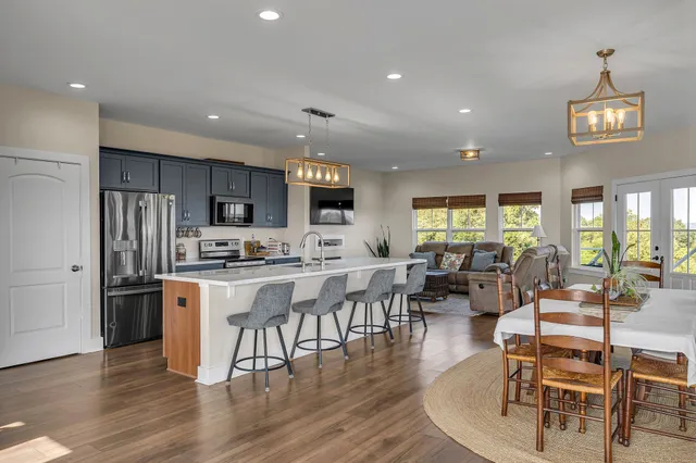 a kitchen with stainless steel appliances a dining table chairs stove and refrigerator