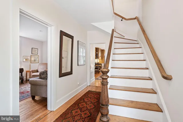 a view of a dining room and livingroom with furniture wooden floor a rug a painting and a chandelier