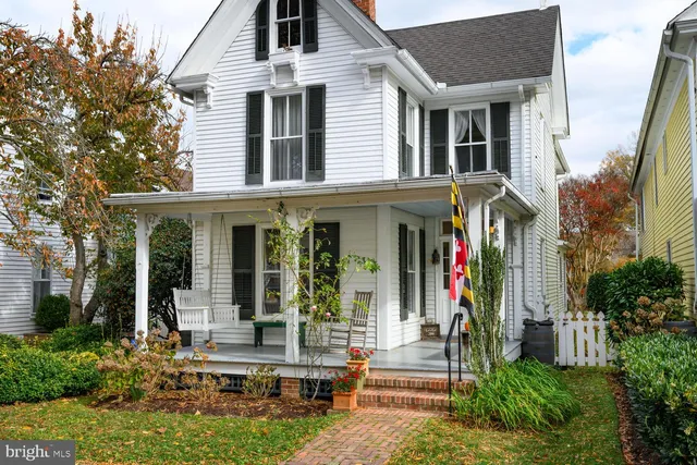 a front view of a house with a yard tree and outdoor seating