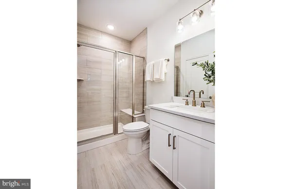 a bathroom with a sink a toilet a mirror and shower